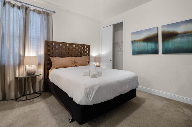 bedroom with baseboards, a closet, and light colored carpet