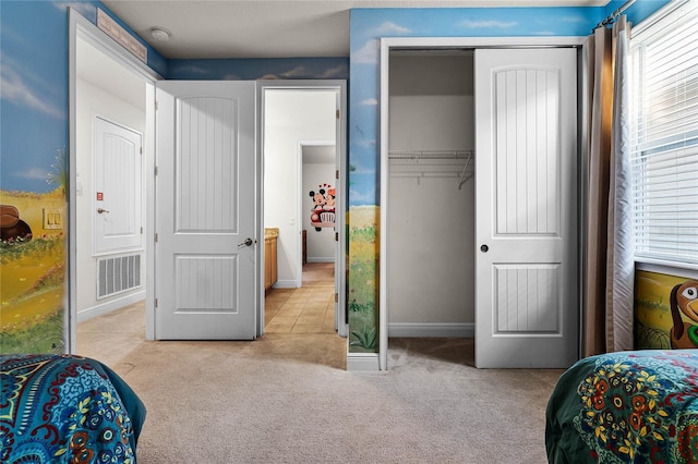 bedroom with baseboards, visible vents, a closet, and light colored carpet