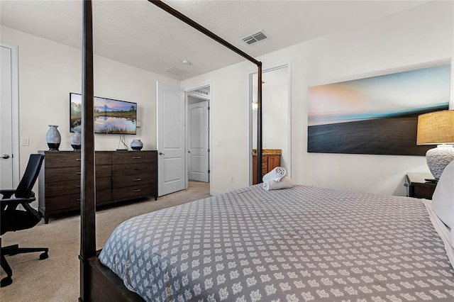 bedroom featuring visible vents, light carpet, and a textured ceiling