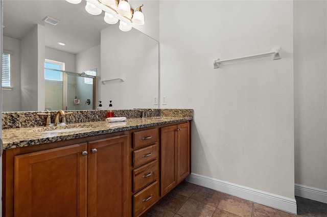 full bath with double vanity, visible vents, a sink, a shower stall, and baseboards