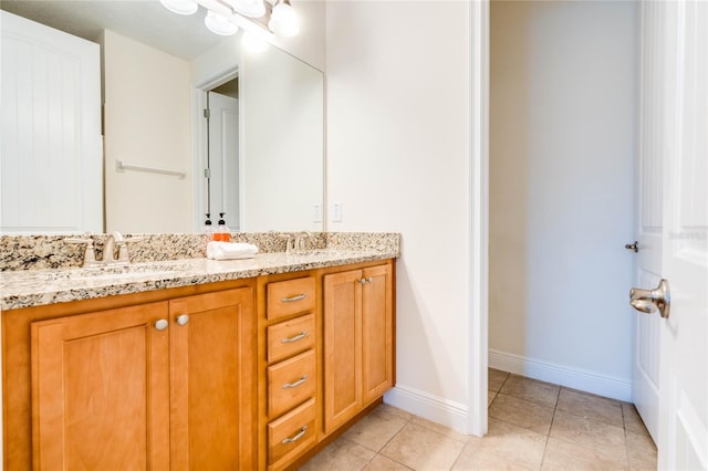 bathroom with tile patterned floors, a sink, baseboards, and double vanity