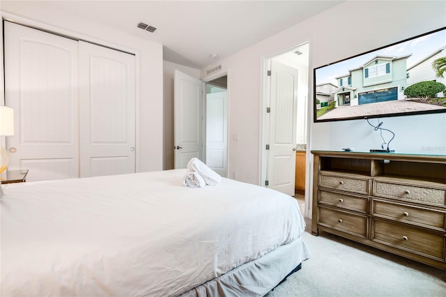 bedroom with visible vents, a closet, and light colored carpet