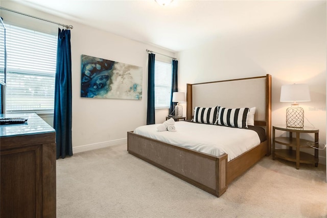 bedroom with baseboards and light colored carpet