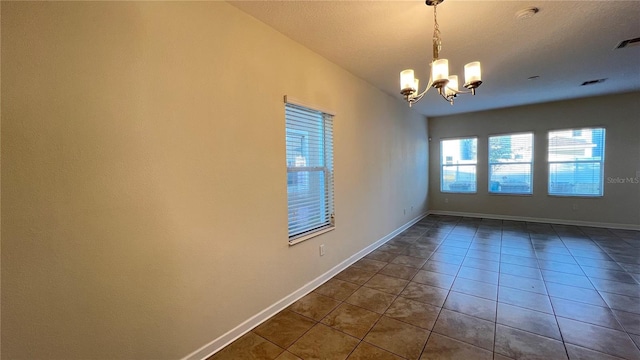 empty room with a notable chandelier, a textured ceiling, vaulted ceiling, and dark tile patterned floors