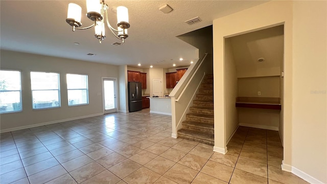 stairway with tile patterned flooring, a notable chandelier, and a textured ceiling