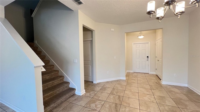 tiled foyer entrance with a chandelier and a textured ceiling