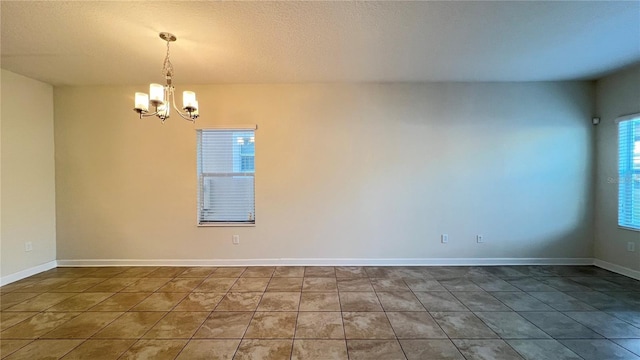 spare room featuring tile patterned floors, a notable chandelier, and a textured ceiling