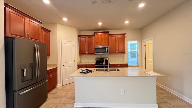 kitchen featuring stainless steel appliances, a kitchen island with sink, sink, and light tile patterned floors