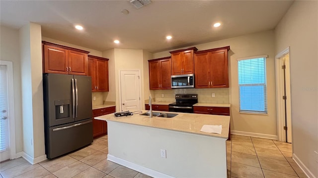 kitchen with tasteful backsplash, an island with sink, sink, light tile patterned floors, and stainless steel appliances