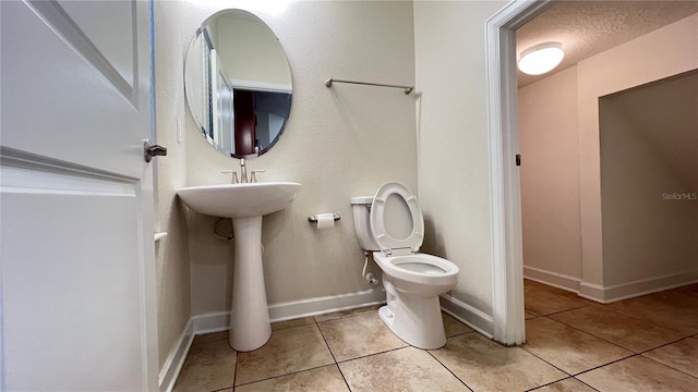 bathroom with tile patterned floors, toilet, and a textured ceiling