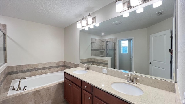 bathroom with independent shower and bath, vanity, and a textured ceiling