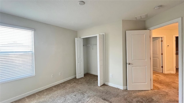 unfurnished bedroom with light carpet and a closet