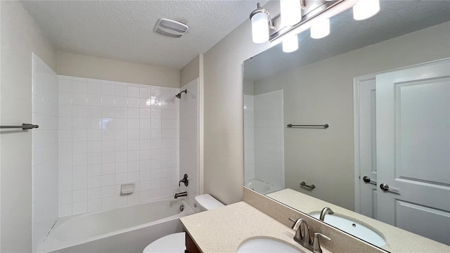 full bathroom featuring vanity, toilet, tiled shower / bath combo, and a textured ceiling