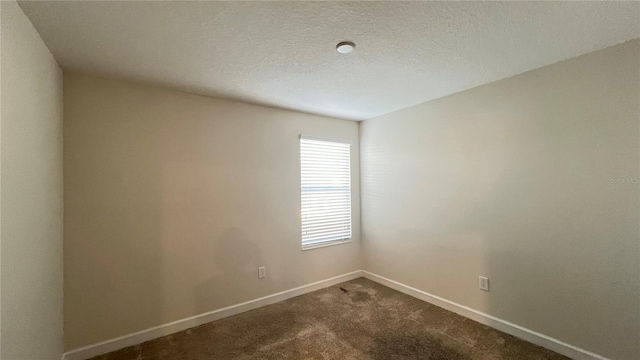 carpeted spare room with a textured ceiling