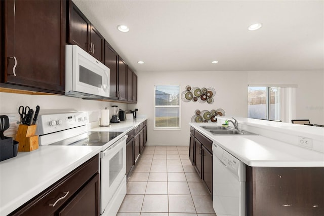 kitchen featuring dark brown cabinets, sink, light tile patterned floors, and white appliances