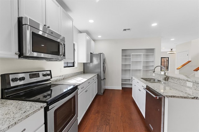 kitchen featuring appliances with stainless steel finishes, sink, white cabinets, dark hardwood / wood-style flooring, and light stone countertops