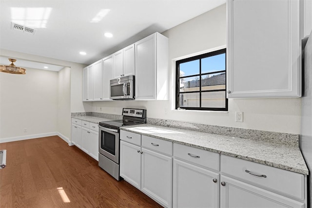 kitchen with light stone counters, appliances with stainless steel finishes, dark wood-type flooring, and white cabinets