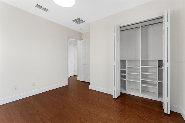 unfurnished bedroom with dark wood-type flooring and a closet