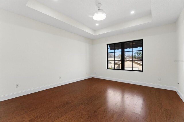 spare room featuring dark wood-type flooring and a tray ceiling