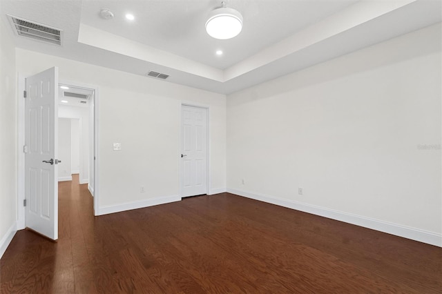 unfurnished room featuring dark hardwood / wood-style flooring and a raised ceiling