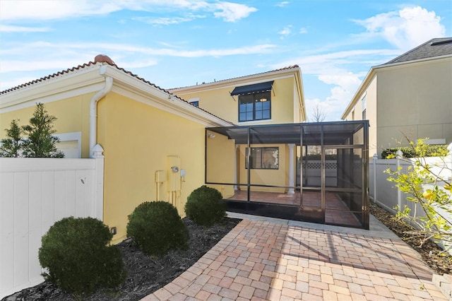 rear view of property featuring a sunroom and a patio area