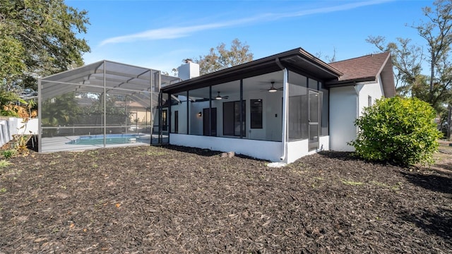 rear view of property with a fenced in pool, ceiling fan, and glass enclosure