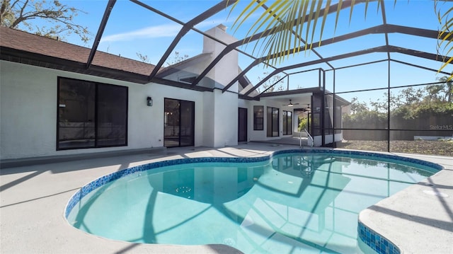 view of swimming pool featuring a patio area, ceiling fan, and glass enclosure