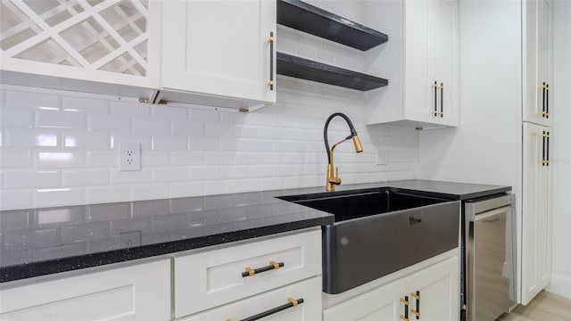 kitchen featuring white cabinetry, sink, decorative backsplash, and dark stone counters