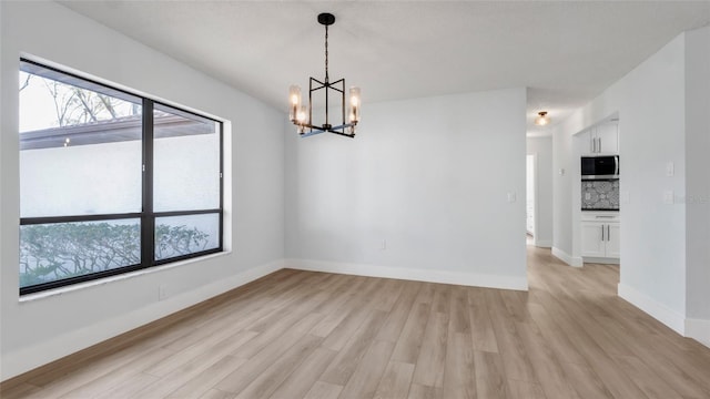 unfurnished dining area featuring a chandelier and light wood-type flooring