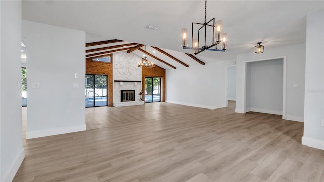 unfurnished living room with a notable chandelier, light wood-type flooring, a fireplace, and beam ceiling