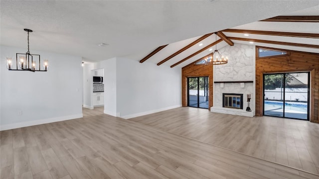 unfurnished living room with high vaulted ceiling, a fireplace, beamed ceiling, a notable chandelier, and light hardwood / wood-style floors