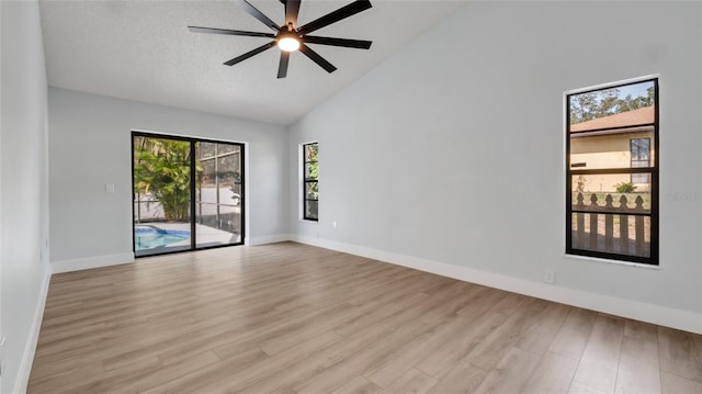 empty room with high vaulted ceiling, a textured ceiling, ceiling fan, and light hardwood / wood-style flooring