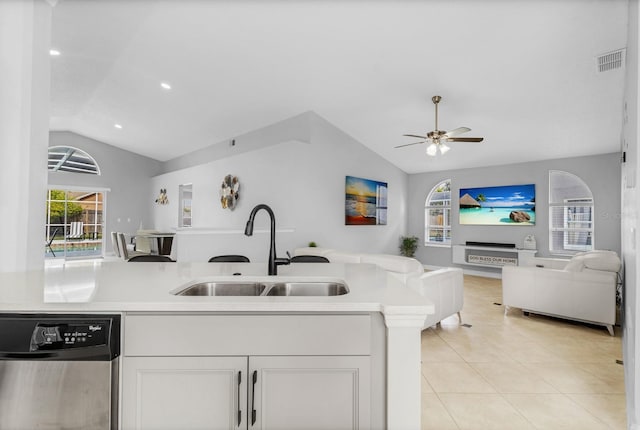 kitchen featuring light tile patterned flooring, sink, vaulted ceiling, stainless steel dishwasher, and white cabinets