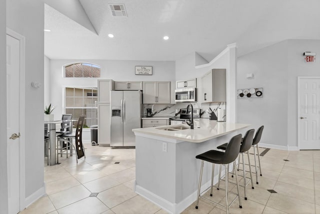 kitchen featuring light tile patterned flooring, sink, a breakfast bar area, kitchen peninsula, and stainless steel appliances