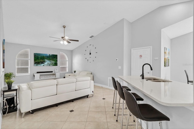 living room featuring ceiling fan, lofted ceiling, sink, and light tile patterned floors