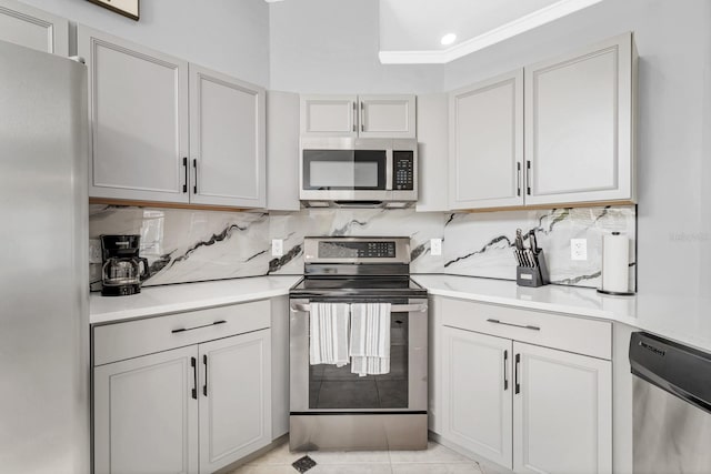 kitchen with tasteful backsplash, light tile patterned floors, stainless steel appliances, and white cabinets