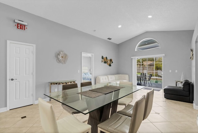 dining room featuring light tile patterned flooring, lofted ceiling, and a textured ceiling