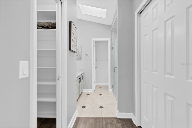 corridor featuring a skylight and light hardwood / wood-style flooring