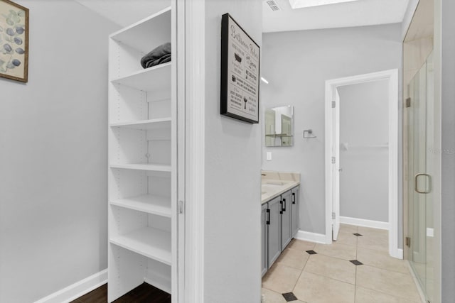 bathroom with tile patterned flooring, vanity, built in shelves, and walk in shower