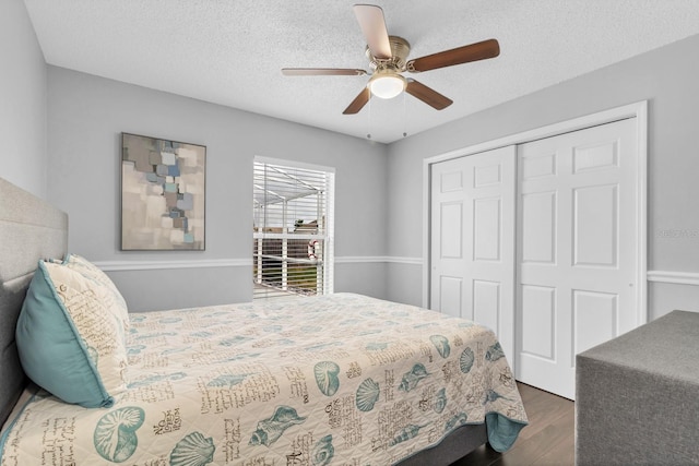 bedroom with ceiling fan, dark wood-type flooring, a closet, and a textured ceiling