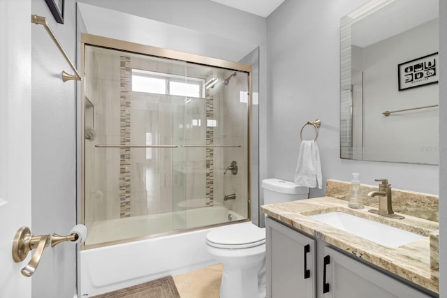 full bathroom with toilet, tile patterned floors, vanity, and bath / shower combo with glass door