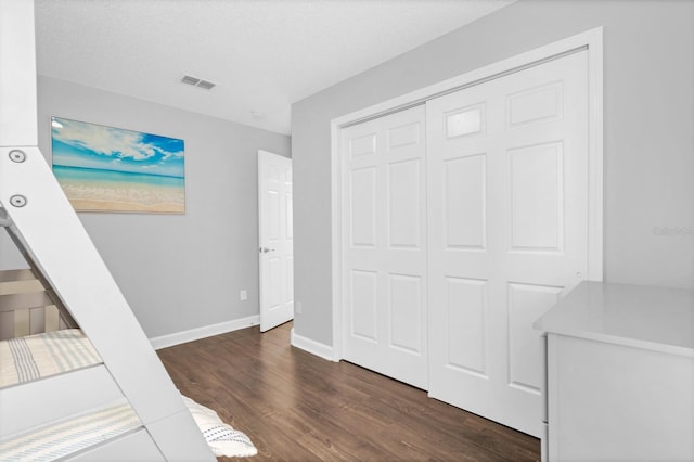 bedroom featuring dark hardwood / wood-style flooring, a closet, and a textured ceiling