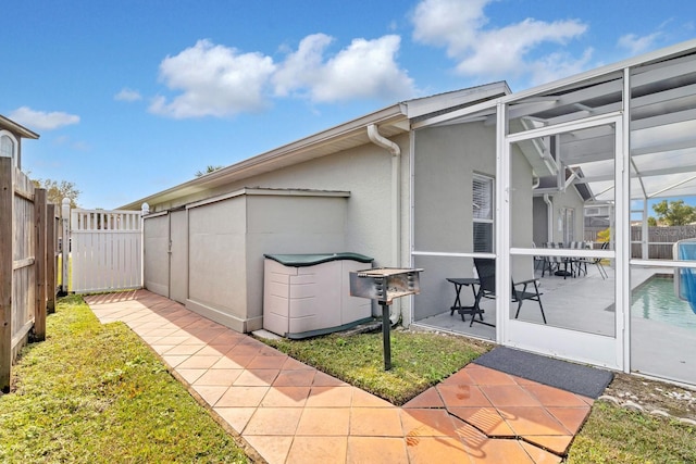 view of side of property featuring a fenced in pool, a lanai, a patio area, and a lawn