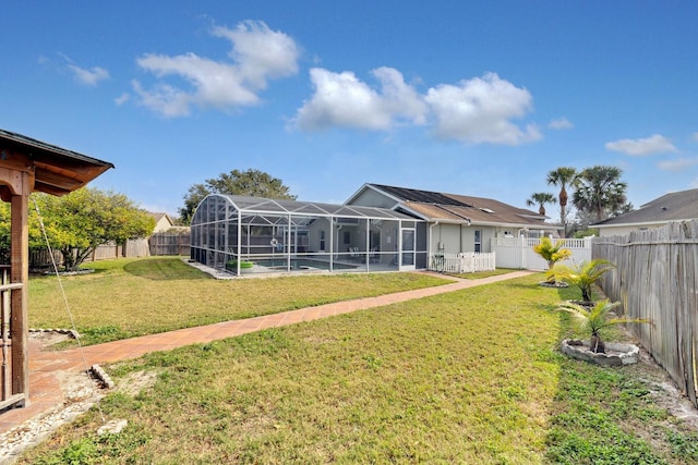 rear view of house featuring a pool, a yard, and glass enclosure