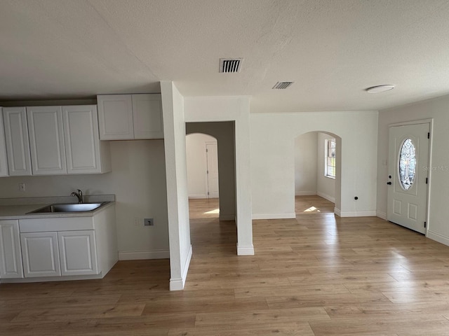 kitchen with white cabinetry, sink, and light hardwood / wood-style flooring