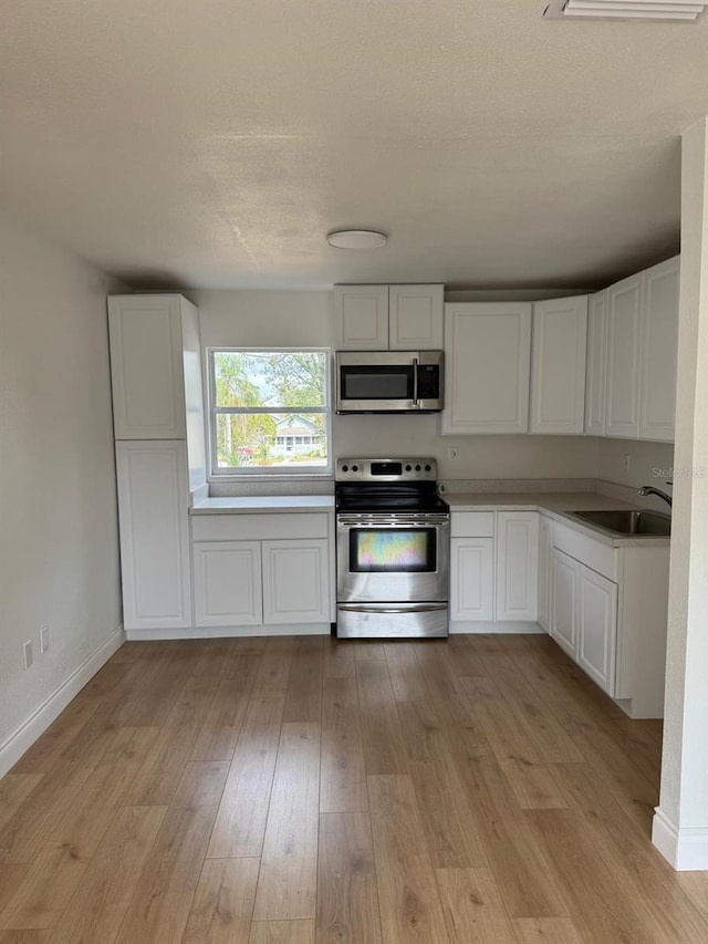 kitchen with white cabinetry, stainless steel appliances, and sink