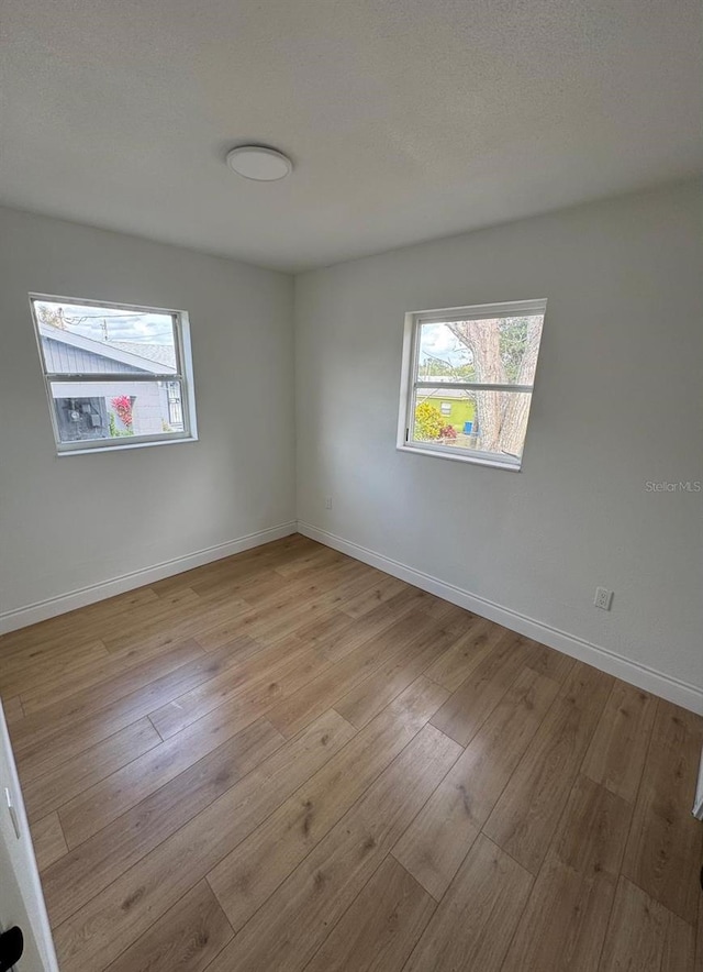 unfurnished room featuring a textured ceiling and light wood-type flooring