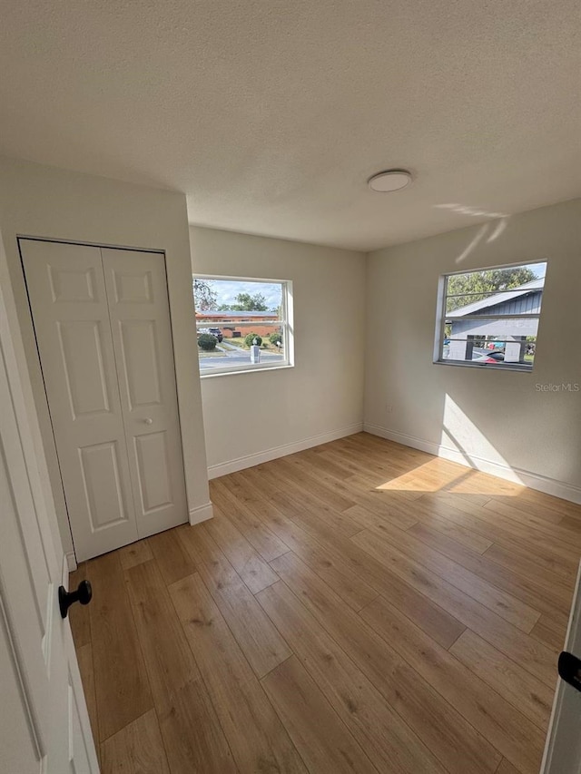 unfurnished room featuring light hardwood / wood-style flooring and a textured ceiling