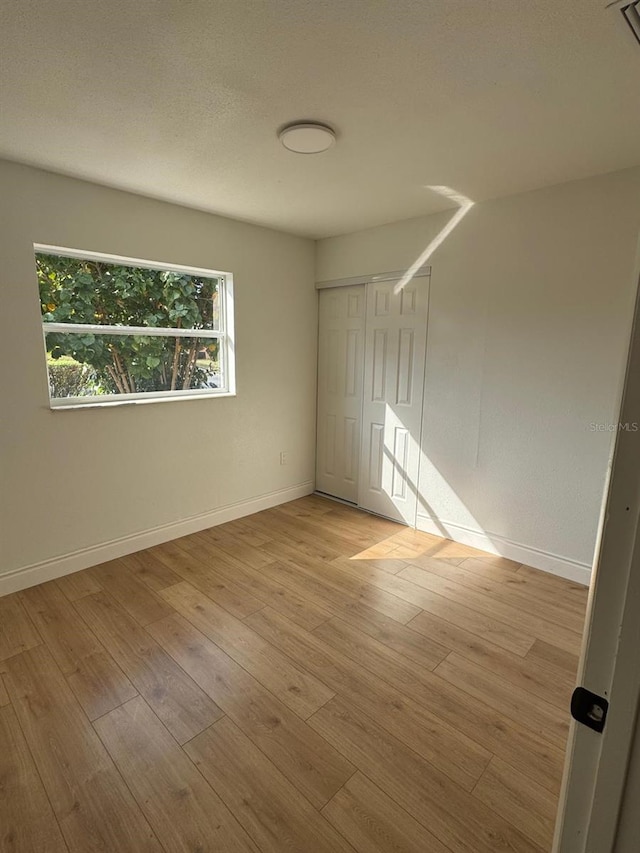 unfurnished room with a textured ceiling and light wood-type flooring