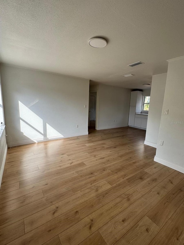 unfurnished room with light hardwood / wood-style floors and a textured ceiling